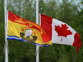 The New Brunswick and Canadian flags fly at half mast outside the Moncton Coliseum in Moncton, N.B. on Monday, June 9, 2014., where a regimental funeral will take place Tuesday for the the three RCMP officers who were slain in Moncton last week. (The Canadian Press/Sean Kilpatrick)