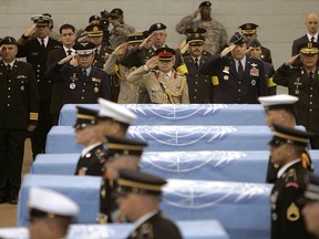 In this April 12, 2007, file photo, delegates of countries which participated in the Korean War salute the United Nations flag-covered coffins of six U.S. soldiers from the Korean War, during a tentative repatriation ceremony at a U.S. military base in Seoul. (AP Photo/You Sung-ho, File)
