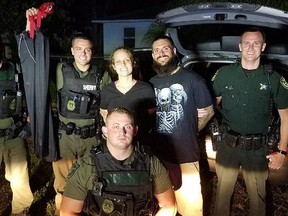 Matthew White, 32, and Amber Taynor, 24, smile and pose with the cops who busted them.
