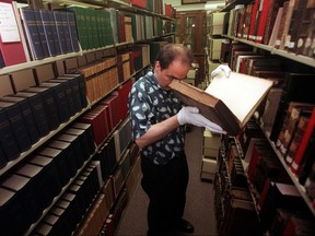 In this June 9, 1999 photo, Greg Priore, an archivist at the Carnegie Library of Pittsburgh, examines books for preservation as part of a $500,000 grant to preserve historic materials. (Sammy Dallal/Pittsburgh Post-Gazette via AP)