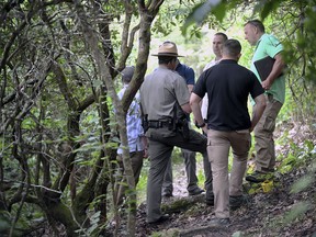 Investigators stand along the trail where a woman's body was found, Thursday, July 26, 2018 near Brevard, N.C.