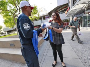 Phoenix firefighter Juan Rodriguez hands out a cooling neckerchief to morning commuter Arielle Thomas early Monday, July 23, 2018, in downtown Phoenix.