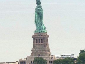 This image taken from video shows people climbing on the side of the Statue of Liberty's pedestal on Wednesday, July 4, 2018 in New York.