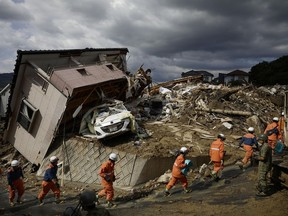 Rescuers conduct a search operation for missing persons in Kumano town, Hiroshima prefecture, western Japan Monday, July 9, 2018. People prepared for risky search and cleanup efforts in southwestern Japan on Monday, where several days of heavy rainfall had set off flooding and landslides in a widespread area.