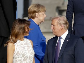 President Donald Trump, right, talks with first lady Melania Trump, left, as German Chancellor Angela Merkel, centre, walks behind them at the Parc du Cinquantenaire in Brussels, Belgium, Wednesday, July 11, 2018.