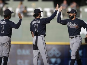 Atlanta Braves' Nick Markakis, right, high-fives Dansby Swanson and Ozzie Albies after a baseball game against the Milwaukee Brewers, Saturday, July 7, 2018, in Milwaukee.