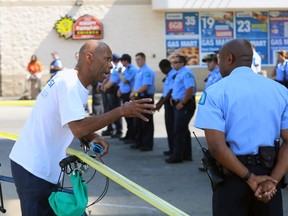 A neighborhood man talks with police who lined up around a Gas Mart at 5745 Delmar Boulevard, Thursday, July 26, 2018 in St. Louis, Mo. (AP Photo/Christian Gooden)