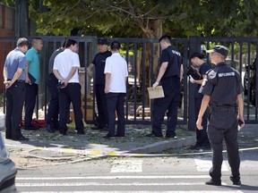 Officials and security personnel stand near the site of reported blast just south of the U.S. Embassy in Beijing, Thursday, July 26, 2018. A fire or possible explosion appears to have taken place outside the U.S. Embassy in Beijing on Thursday.