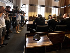 Photographers take pictures of the a man and a woman in the court in Freiburg, southern Germany, Tuesday, Aug. 7, 2018 before they were sentenced to long-term prison sentence for for offering the 9-year-old son of the woman for raping by pedophiles. (Patrick Seeger/dpa via AP)