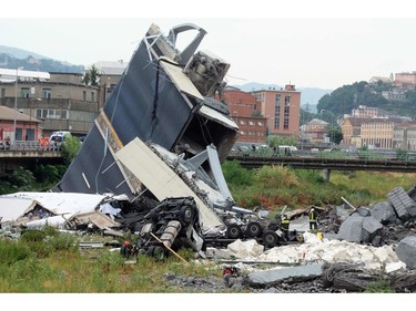 Rescuers are at work amid the rubble of a section of a giant motorway bridge that collapsed earlier, on August 14, 2018 in Genoa. - Rescuers scouring through the wreckage after part of a viaduct of the A10 freeway collapsed said there were "tens of victims", while images from the scene showed an entire carriageway plunged on to railway lines below.