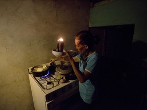 In this Aug. 19, 2018 photo, Mireya Marquez uses candlelight to cook her dinner of boiled "cassava," also known as yuca and manioc, during a blackout in Maracaibo, Venezuela. For months Maracaibo's residents have endured rolling blackouts, but things turned dire on August 10 when a fire destroyed a main power line supplying the city of 1.5 million people.