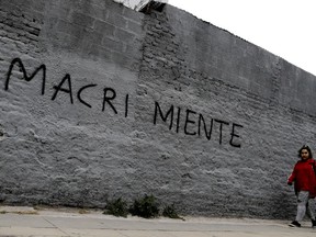 A woman walks past a wall spray-painted with a message that reads in Spanish: "Macri lies" in reference to the country's president, Mauricio Marci, in Buenos Aires, Argentina, Thursday, Aug. 30, 2018.