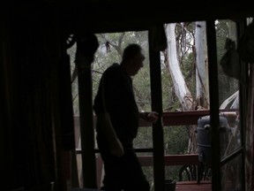 In this Thursday, May 17, 2018, photo, Peter Peacock closes his balcony doors as he prepares to go into the city to meet with Gypsy Diamond, 36, in Melbourne, Australia. Peacock, who donated sperm anonymously around 1980, was recently contacted by Diamond, his biological daughter, after a new law in Australia retroactively removed the anonymity granted to sperm donors decades ago.