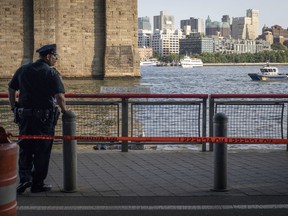 A New York Police Department officer stands guard as authorities investigate the death of a baby boy who was found floating in the water near the Brooklyn Bridge in Manhattan, on Sunday, Aug. 5, 2018, in New York.