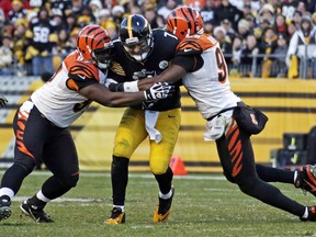 This Dec. 23, 2012 file photo shows Pittsburgh Steelers quarterback Ben Roethlisberger being tackled after a 4-yard scramble, by Cincinnati Bengals defensive tackle Geno Atkins, left, and defensive end Carlos Dunlap during the fourth quarter of an NFL football game in Pittsburgh.