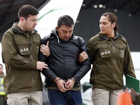 Photo released by Aton Chile of Chilean Franco Sepulveda, 29, as he is escorted upon his arrival in Santiago after being arrested in Antofagasta for allegedly making false bomb threats which forced emergency operations in nine commercial flights on August 17, 2018. (Javier TORRES / ATON CHILE / AFP)