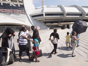 A group of asylum seekers leave Olympic Stadium to go for a walk, in Montreal on Wednesday, August 2, 2017. (Ryan Remiorz/The Canadian Press)