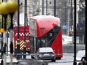 A car that crashed into security barriers outside the Houses of Parliament stands to the right of a bus in London, Tuesday, Aug. 14, 2018. London police say that a car has crashed into barriers outside the Houses of Parliament and that there are a number of injured.