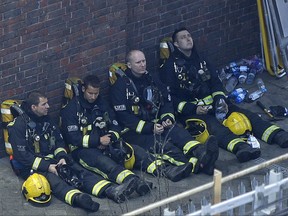 Firefighters rest as they take a break in battling a massive fire that raged in a high-rise apartment building in London on Wednesday, June 14, 2017.
