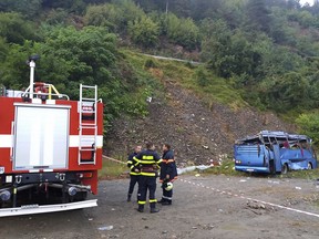 In this handout photo provided by the Bulgarian Interior Ministry, firefighters near the scene where a bus crashed and overturned, near the town of Svoge, Saturday, Aug. 25, 2018.  Bulgaria's health minister says a tourist bus has flipped over on a highway near Sofia, the capital, killing at least 15 people and leaving 27 others injured. Police said a bus carrying tourists on a weekend trip to a nearby resort overturned and then fell down a side road 20 meters (66 feet) below the highway.