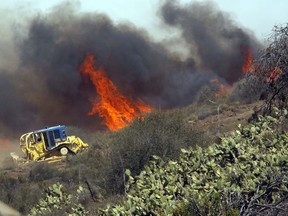 In this May 2, 2013 file photo, a bulldozer helps clear a hill near a fire in Thousand Oaks, Calif. Not all firefighters carry a hose or a shovel.