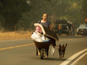 A woman, who declined to give her name, evacuates from Lakeport, Calif., as the River Fire approaches, Tuesday, July 31, 2018. (AP Photo/Noah Berger)