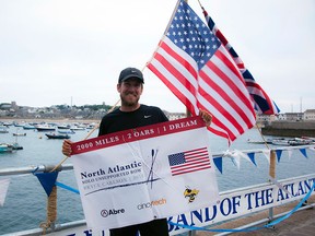 In this Saturday, Aug. 4, 2018 photo provided by Bryce Carlson Adventures, Bryce Carlson poses for a photo after completing his solo unsupported row across the Atlantic, at St Mary's Harbour, Isle of Scilly, England.