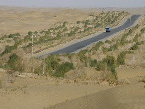 A truck crosses the Taklamakan Desert in China's far west Xinjiang province in Central Asia, Oct. 12, 2006, on the Cross Desert Highway, completed in the mid-1990's to help facilitate the extraction of oil from beneath the desert.