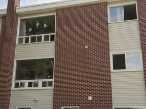 A window at an apartment building complex on Brookside Drive where four people died, including two police officers, in a shooting last Friday, is shown with evidence markers designating bullet holes after police removed barricades allowing residents to return in Fredericton, N.B., on Tuesday, August 14, 2018.