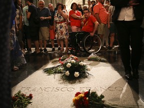 People stand around the tomb of former Spanish dictator Francisco Franco inside the basilica at the the Valley of the Fallen monument near El Escorial, outside Madrid, Friday, Aug. 24, 2018. (AP Photo/Andrea Comas)