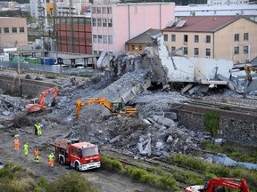 Firefighters remove debris of the collapsed Morandi highway bridge in Genoa, Italy, Thursday, Aug. 16, 2018.