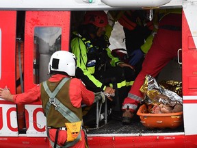Firefighters load an injured person on a helicopter after the Morandi highway bridge collapsed in Genoa, northern Italy, Tuesday, Aug. 14, 2018.