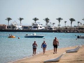 File photo of tourists walking along the beach in Egypt's Red Sea resort of Hurghada on February 19, 2018. / AFP PHOTO / MOHAMED EL-SHAHED
