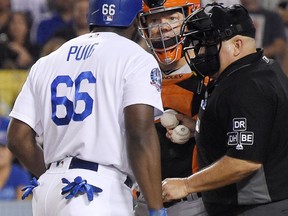 Los Angeles Dodgers' Yasiel Puig, left, and San Francisco Giants catcher Nick Hundley, center, argue while home plate umpire Eric Cooper gets between them during the seventh inning, Tuesday, Aug. 14, 2018, in Los Angeles.