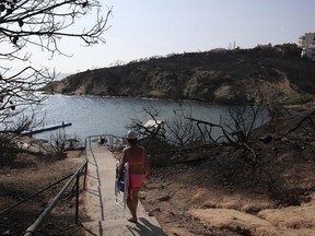 A woman walks towards a beach in Rafina, east of Athens, Wednesday, Aug. 1, 2018, ten days after the wildfire. (AP Photo/Thanassis Stavrakis)