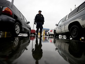In this Dec. 3, 2014 picture, an Immigration and Customs Enforcement (ICE) agent watches cars as they wait to enter the United States from Tijuana, Mexico through the San Ysidro port of entry in San Diego. (AP Photo/Gregory Bull)