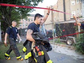 Chicago firefighters walk under tape at the scene of a fire that killed several people, including multiple children, Sunday, Aug. 26, 2018, in Chicago.