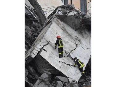 Rescuers work among the rubble of the collapsed Morandi highway bridge in Genoa, northern Italy, Tuesday, Aug. 14, 2018.