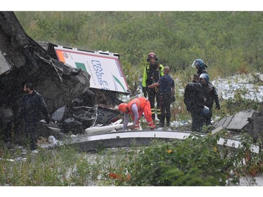 Rescuers work among the rubble of the collapsed Morandi highway bridge in Genoa, northern Italy, Tuesday, Aug. 14, 2018.