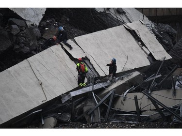 Rescues work among the debris of the collapsed Morandi highway bridge in Genoa, Tuesday, Aug. 14, 2018.