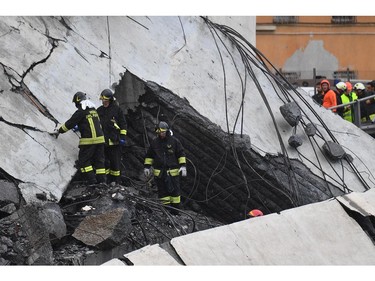 Rescuers work among the rubble of the collapsed Morandi highway bridge in Genoa, northern Italy, Tuesday, Aug. 14, 2018. A large section of the bridge collapsed over an industrial area in the Italian city of Genova during a sudden and violent storm, leaving vehicles crushed in rubble below. (Luca Zennaro/ANSA via AP) ORG XMIT: GEO123