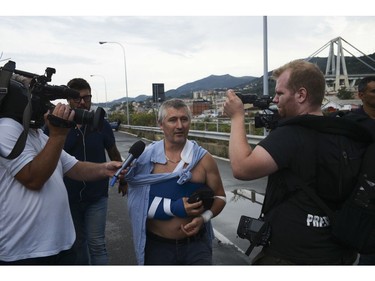 An injured man talks to reporters as he leave the site where the Morandi highway bridge collapsed in Genoa, northern Italy, Tuesday, Aug. 14, 2018.