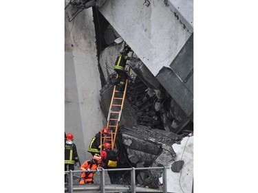 Rescues work among the debris of the collapsed Morandi highway bridge in Genoa, Tuesday, Aug. 14, 2018.