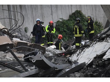 Rescues work among the debris of the collapsed Morandi highway bridge in Genoa, Tuesday, Aug. 14, 2018.