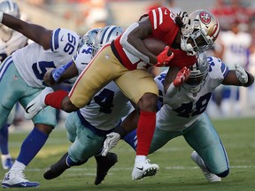 San Francisco 49ers running back Jerick McKinnon, foreground, carries against Dallas Cowboys defensive end Datone Jones, linebacker Jaylon Smith, centre left, and linebacker Joe Thomas during the first half of an NFL preseason football game in Santa Clara, Calif., Thursday, Aug. 9, 2018.