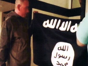 In this July 8, 2017 file image taken from FBI video and provided by the U.S. Attorney's Office in Hawaii on July 13, 2017, Army Sgt. 1st Class Ikaika Kang holds an Islamic State group flag after allegedly pledging allegiance to the terror group at a house in Honolulu.