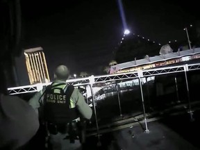 In this Sunday, Oct. 1, 2017, image taken from police body cam video released Wednesday, July 25, 2018, by the Las Vegas Metropolitan Police Department, an armed law enforcement official stands at the scene as authorities direct concertgoers to safety and search for what they thought were multiple shooters inside and outside a Las Vegas Strip hotel, where a gunman firing from upper-floor windows killed 58 people and injured hundreds. (Las Vegas Metropolitan Police Department via AP)