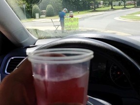This Saturday, Aug. 4 2018, photo provided by James Castellano, of Monroe, N.C., shows a drink he bought from a boy, background, in Monroe. A teenager who held up the North Carolina lemonade stand for $17 was still at large Monday, Aug. 6, and authorities said they hoped to track him through surveillance footage and possible DNA and fingerprint tests.