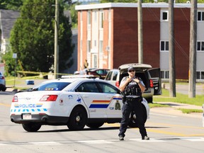 Police and RCMP officers survey the area of a shooting in Fredericton, N.B. on Friday, August 10, 2018. (THE CANADIAN PRESS/Keith Minchin)