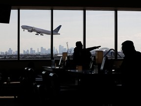 In this July 18, 2018, file photo, a United Airlines commercial jet takes off as travelers sit at a gate in Terminal C of Newark Liberty International Airport in Newark, N.J.